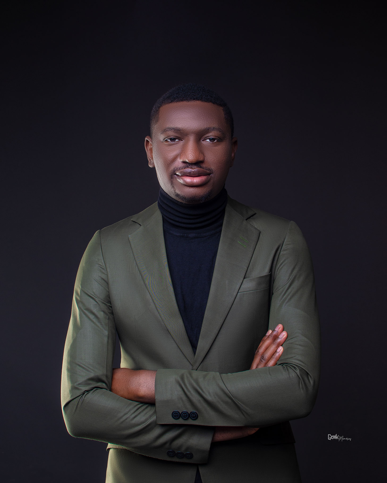 Portrait of Emmanuel Eruemulor wearing an olive suit and black roll-neck